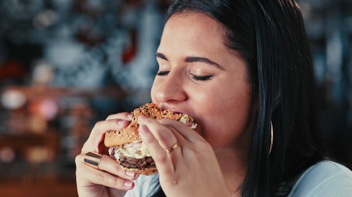 一名年轻女子在餐厅享用汉堡的4k视频片段