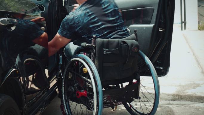 残疾人靠自己的轮椅自己下车。