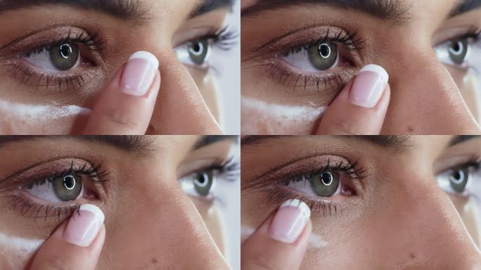 4k视频画面，一名妇女在工作室背景下在眼睛下涂抹保湿霜