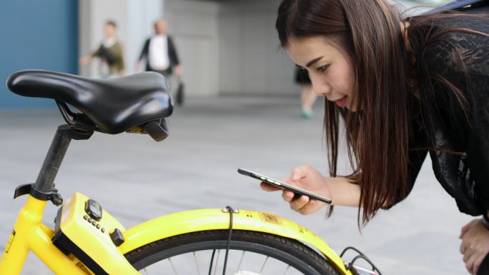 女性使用智能手机扫描城市共享单车二维码