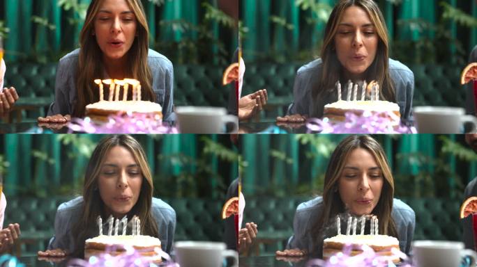 一个美丽的女人庆祝生日的特写镜头，吹灭蛋糕上的蜡烛，看起来很开心