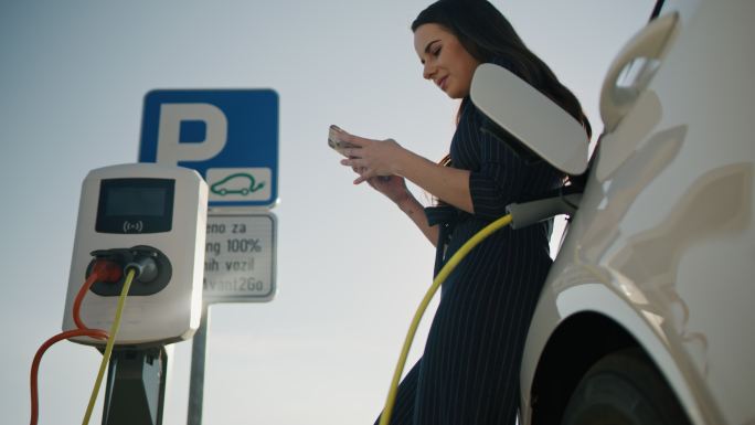 SLO-MO：一位年轻女子在等待汽车充电时使用智能手机