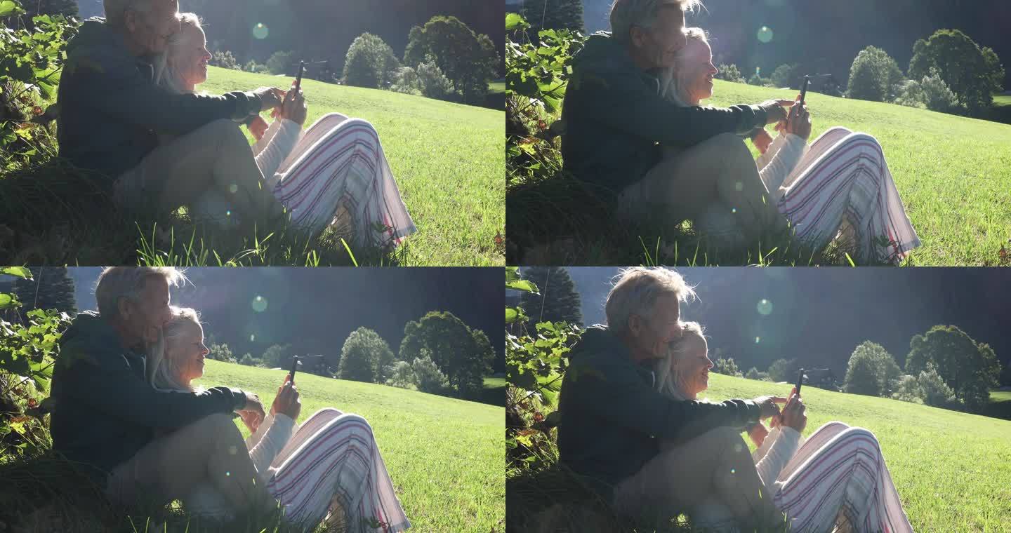 夫妇在山间草地放松，看智能手机