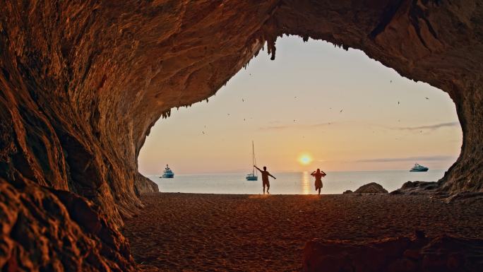 意大利撒丁岛卡拉卢纳，一对情侣在海滩上跑步的慢镜头。