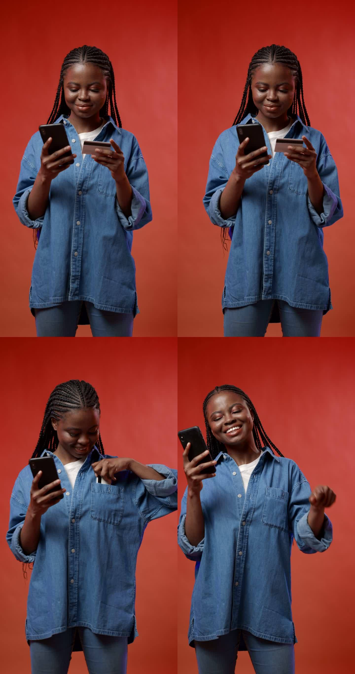 一段垂直视频，一个快乐、有魅力、皮肤黝黑的学生用红色背景的信用卡在智能手机上购买了她非常想要的东西