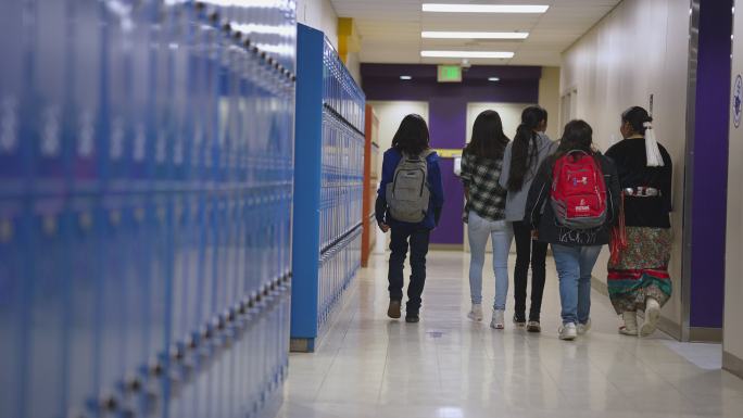 一群中学生和高中生穿过学校走廊