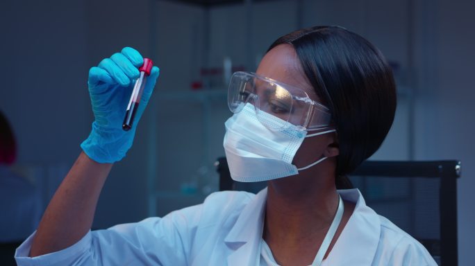 一位年轻的非洲裔美国女微生物学家正在看一个带有血样的试管