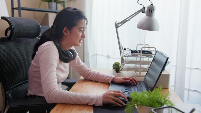 一个十几岁的女孩在家里使用笔记本电脑时正在思考。找工作。兼职工作。在线学习，在线购物。
