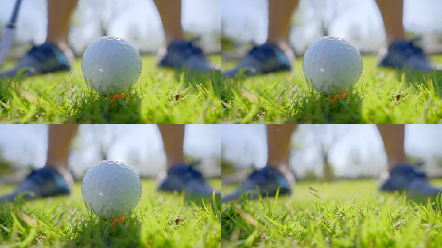 高尔夫球击球时，球打离发球台的特写镜头。高尔夫球杆以超慢动作击打高尔夫球，草地和球座上升到空中。早晨