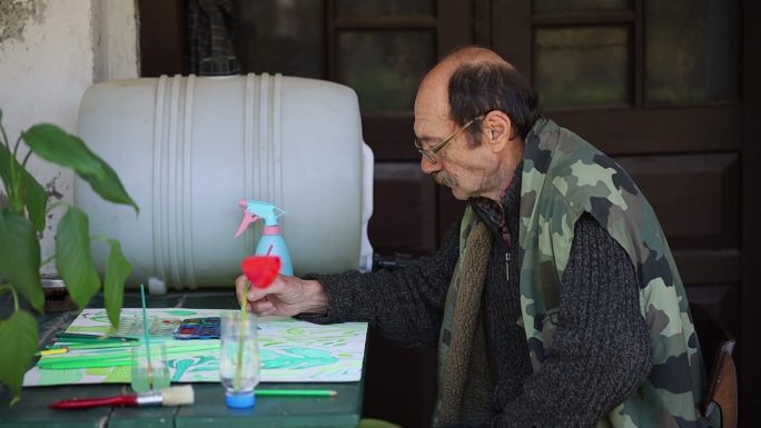 一位退休老人正在画他的画