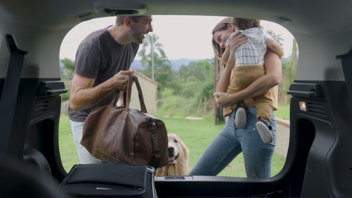 一个快乐的巴西家庭带着一只宠物来到农村，男人卸下袋子，而女人抱着孩子