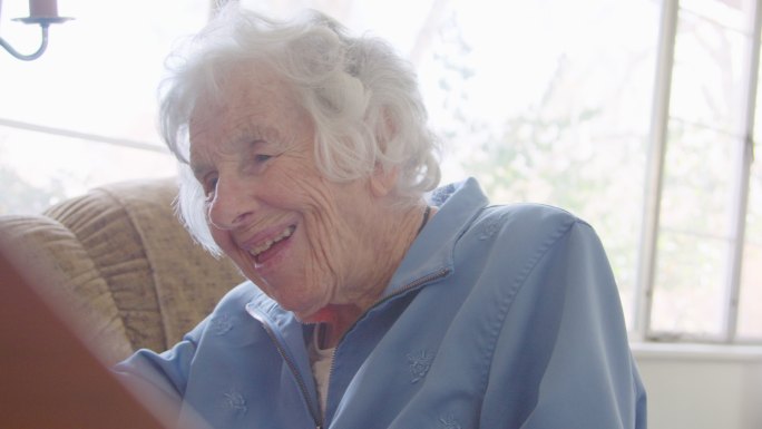 一位快乐的老年妇女在家中弹奏钢琴键盘时的手持照片