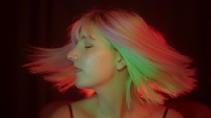 一个年轻漂亮的女人的肖像，五颜六色的发型被五颜六彩的霓虹灯照亮
