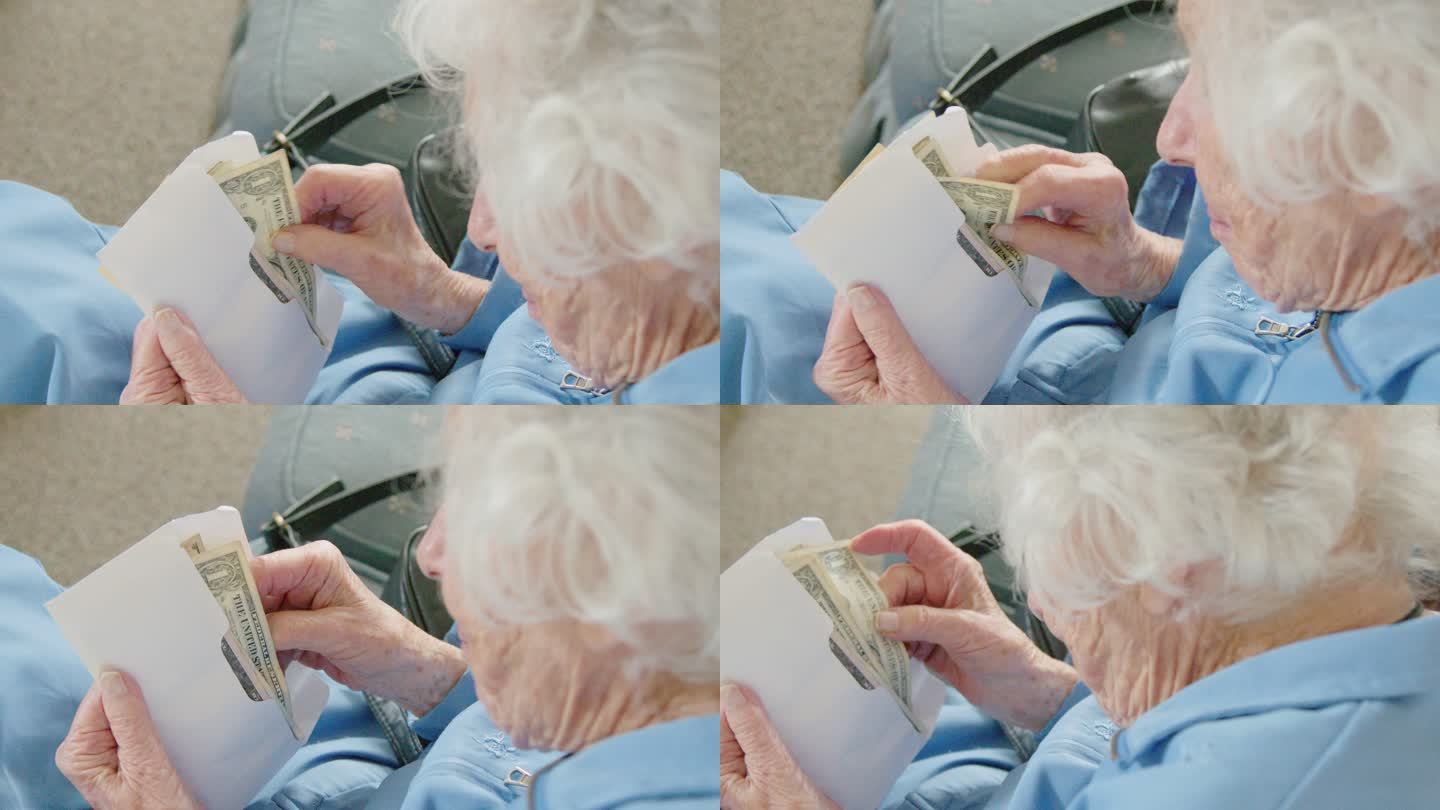 一位年长的高加索妇女看着一张一美元的钞票，同时数着信封里的现金