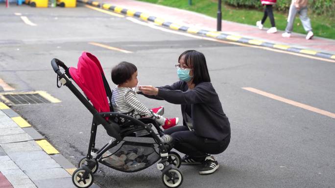 疫情防控下妈妈给婴儿车里的女儿戴口罩
