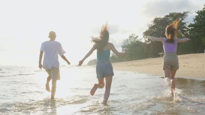 一群亚洲年轻男女一起在海滩上跑步。吸引人的朋友：旅行者在海边散步和玩耍时感到快乐，在热带海岛享受假期