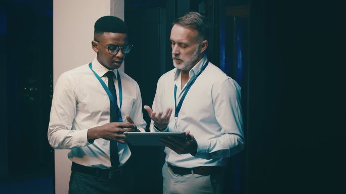两名男子在服务器室工作时使用数字平板电脑的4k视频片段
