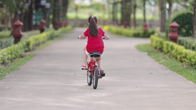 快乐的亚洲女孩骑自行车在公园