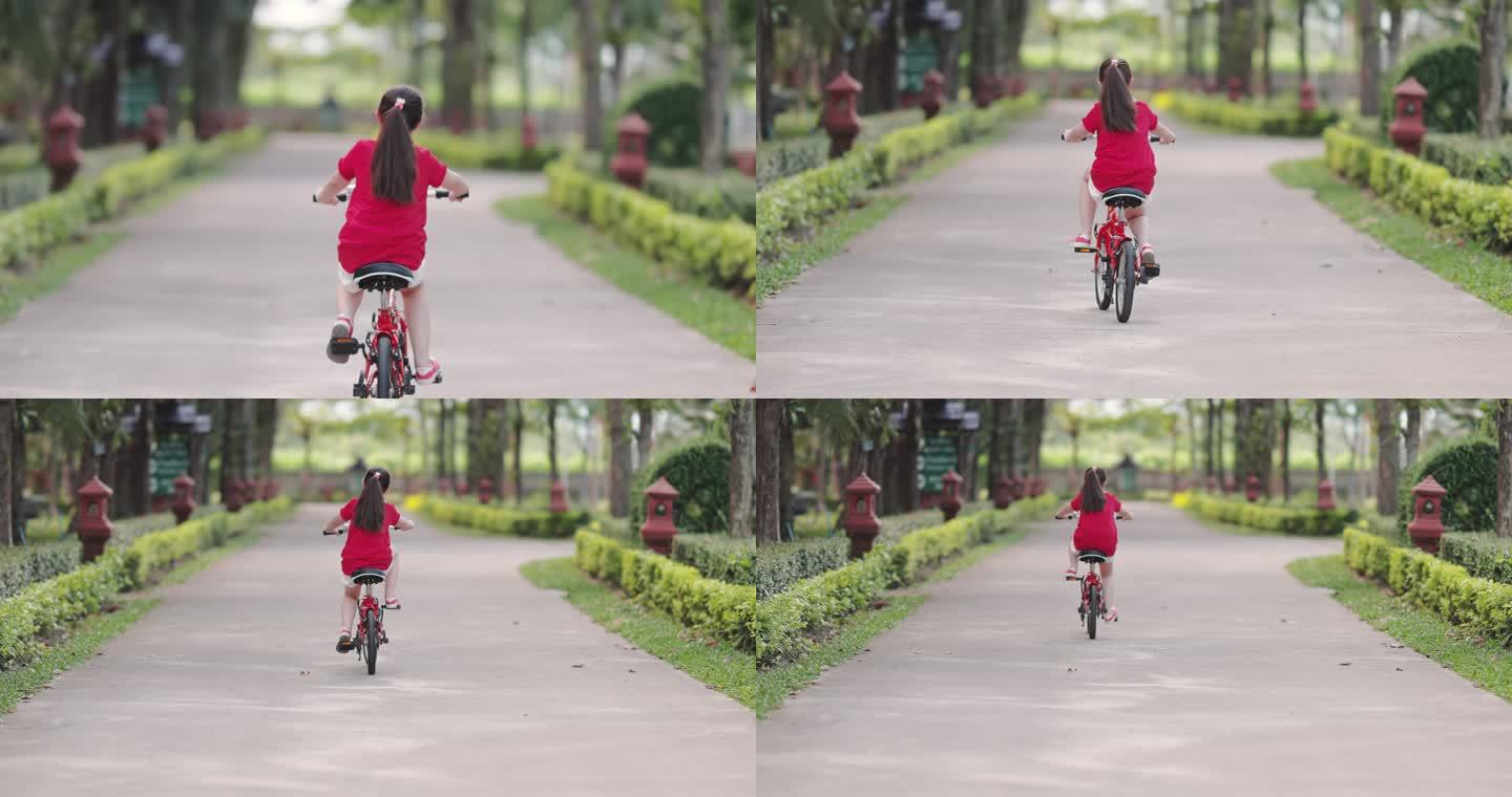 快乐的亚洲女孩骑自行车在公园