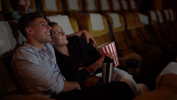 在电影院看电影的年轻情侣。