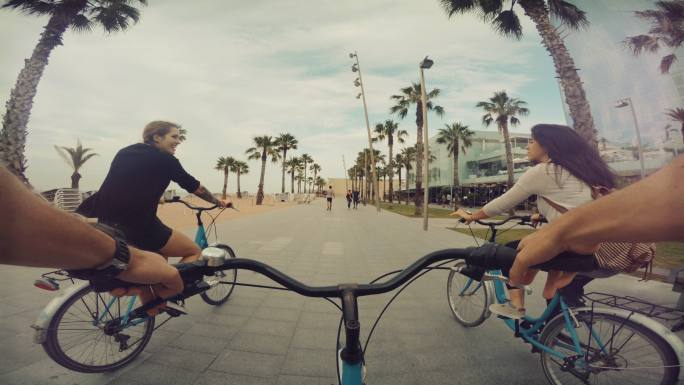 POV与朋友在西班牙巴塞罗那的巴塞洛内塔海滩骑自行车