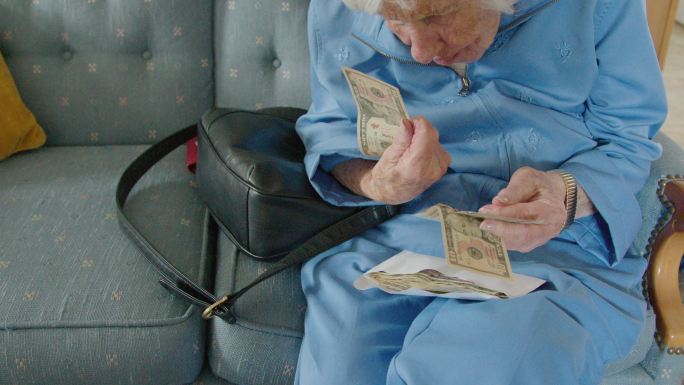 一位年长的高加索人妇女仔细地看着信封里的一堆现金