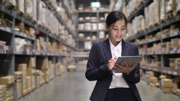 在仓库里，亚洲商业女性手持数字平板电脑。检查库存订单
