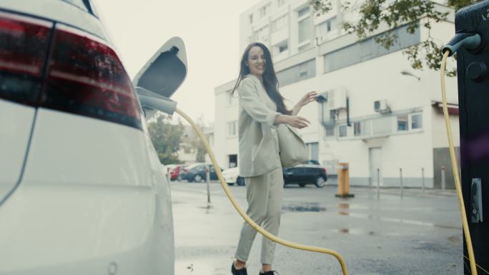 SLO-MO：一位年轻女子在雨中跳舞，她的电动车正在充电
