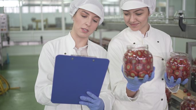 女工在工厂检查装满填充辣椒的罐子的重量