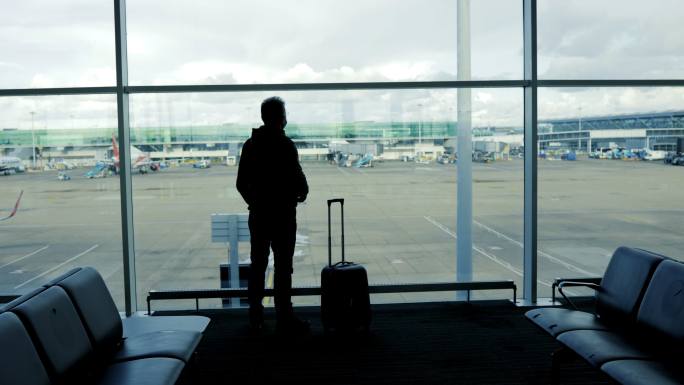 一名中年男子在机场向窗口挥手告别，这是一个旅游概念，