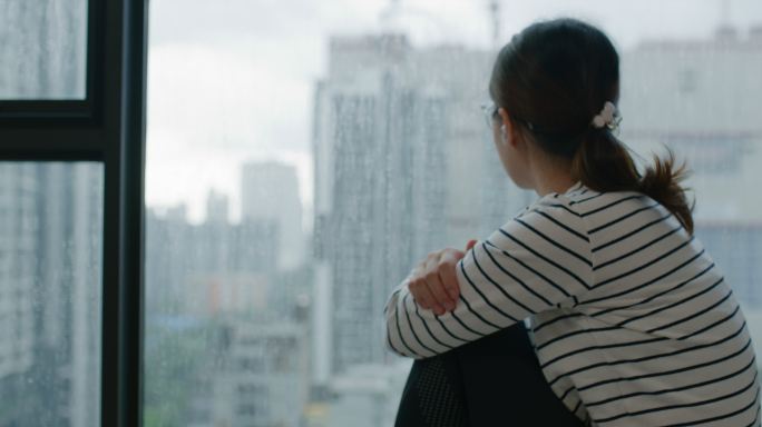 一个悲伤的女人看着外面的雨天