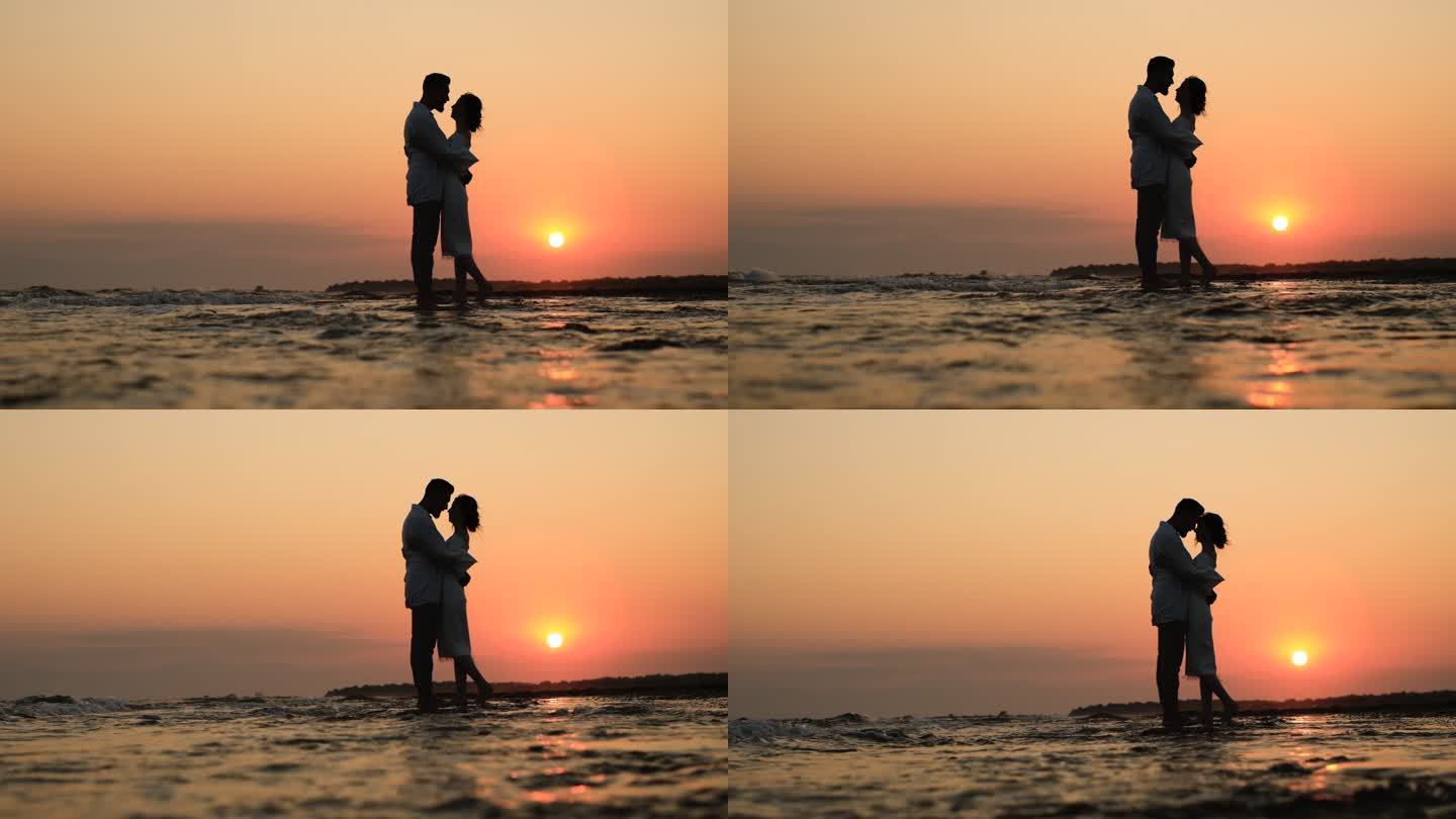 日落时海滩上一对浪漫情侣的侧影
