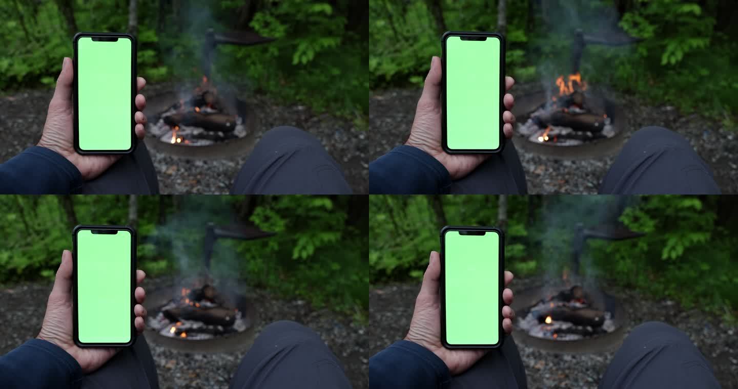 营火旁的彩色键绿色屏幕手机上的人手阅读特写
