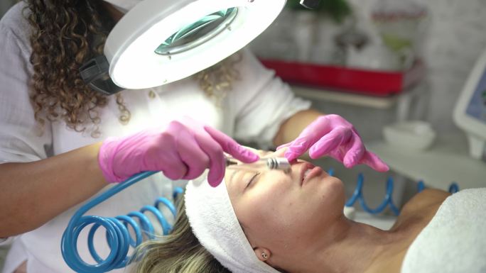 美容师在女性客户脸上做微晶磨皮治疗