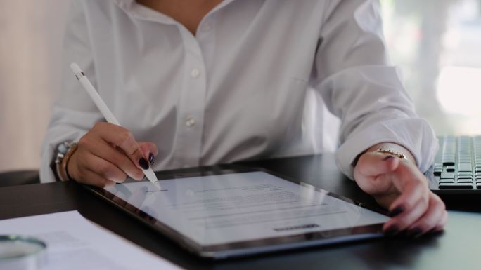女商人使用数字平板电脑在办公室签署法律文件