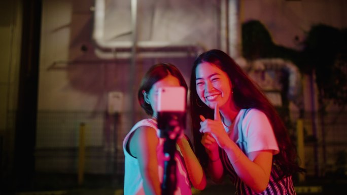 女性朋友晚上在城市社交媒体上跳舞和视频聊天