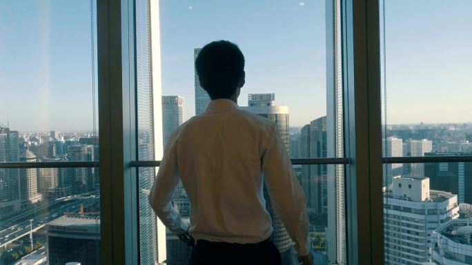一个商人从办公室的窗户望着城市的景色