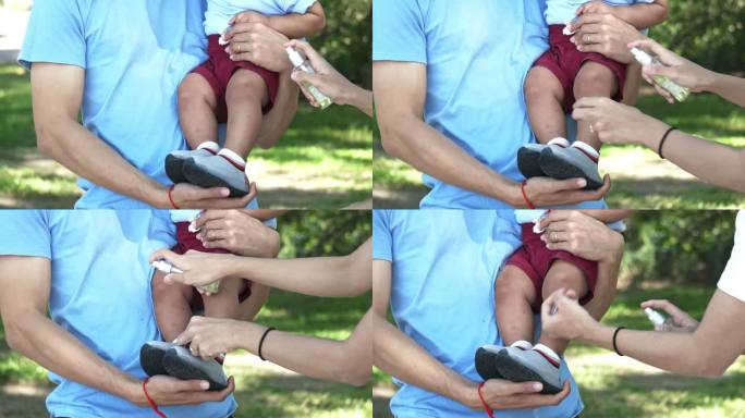 在公共公园，母亲在儿子身上涂抹驱虫剂，慢镜头