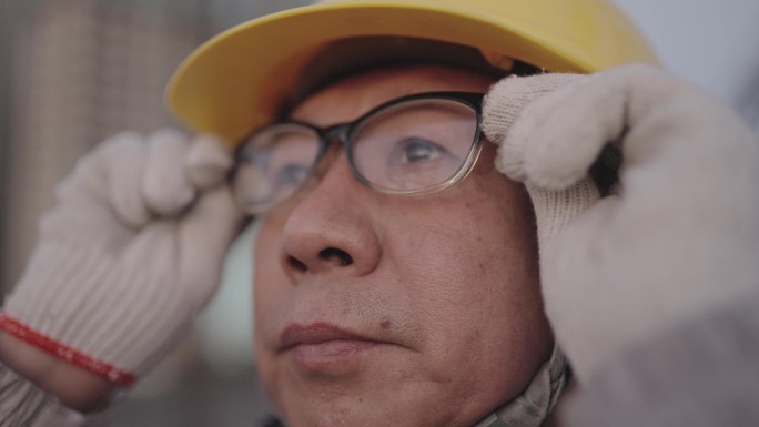 这位亚洲高级工程师手拿眼镜，晚上在电站工作