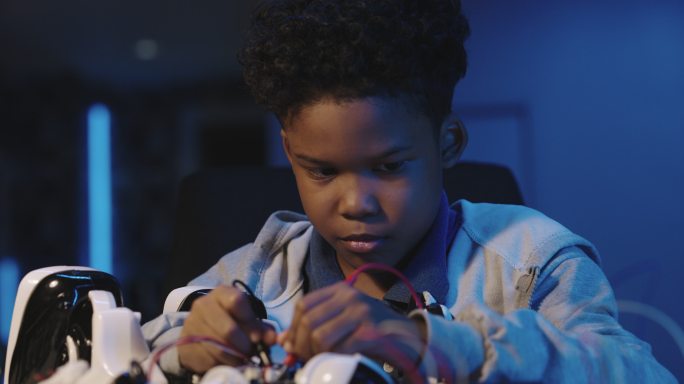 9岁男孩在家上学时制造人工机器人的非裔美国人晚上在家工作到很晚。儿童、教育、技术、科学、STEM教育