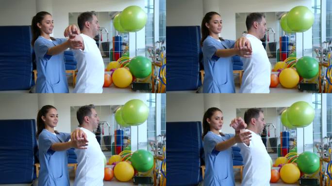 友好的女性治疗师在物理康复治疗期间帮助患者锻炼手臂、肩膀和背部