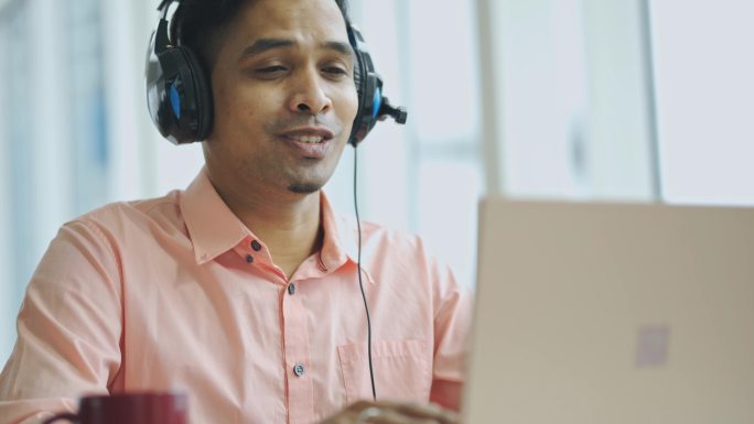 亚洲印度男性客户服务代表通过耳机和笔记本电脑与客户在线交流