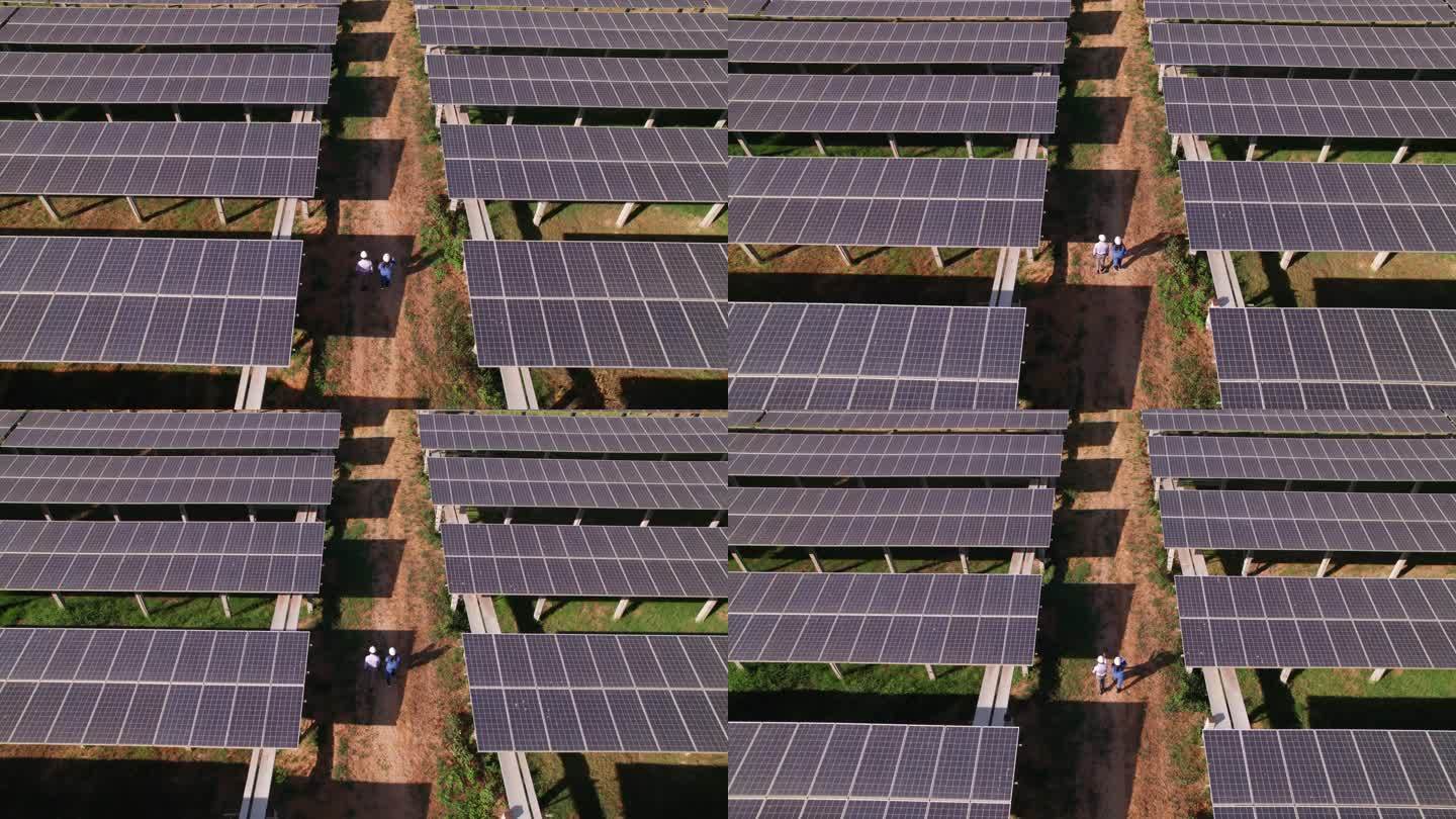 工程师和技术人员在太阳能电池板阴影下检查太阳能电池板农场的鸟瞰图