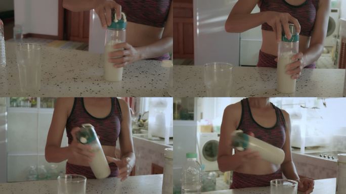 一位穿着运动服的亚洲年轻女子在家的厨房里用蛋白粉制作奶昔。