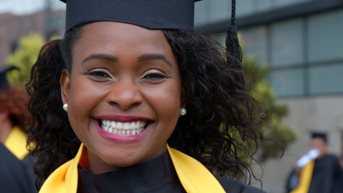 黑色，美丽的女毕业生，在大学毕业典礼后面对镜头