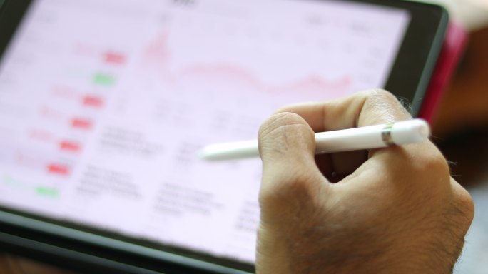 亚洲商人使用平板电脑在咖啡店工作、查看股票趋势图和财务分析