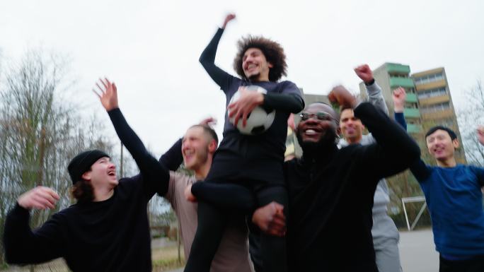 快乐的男性足球运动员举起队友庆祝胜利