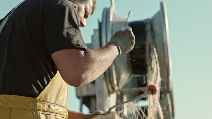 中年渔民用绞盘卷网