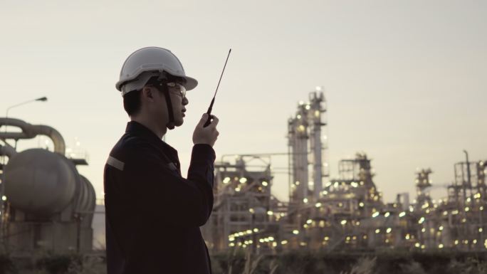石油和天然气工业中的石油炼油厂工程师工人使用个人安全设备PPE进行检查，遵循平板电脑检查表，通过无线