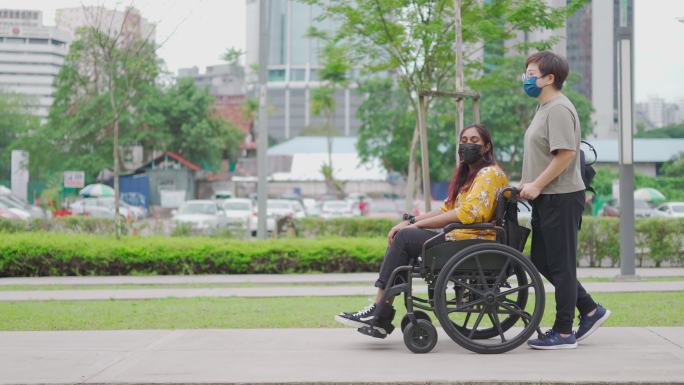 一名亚裔中国中年妇女在城市街道上推着她的印度残疾女性朋友